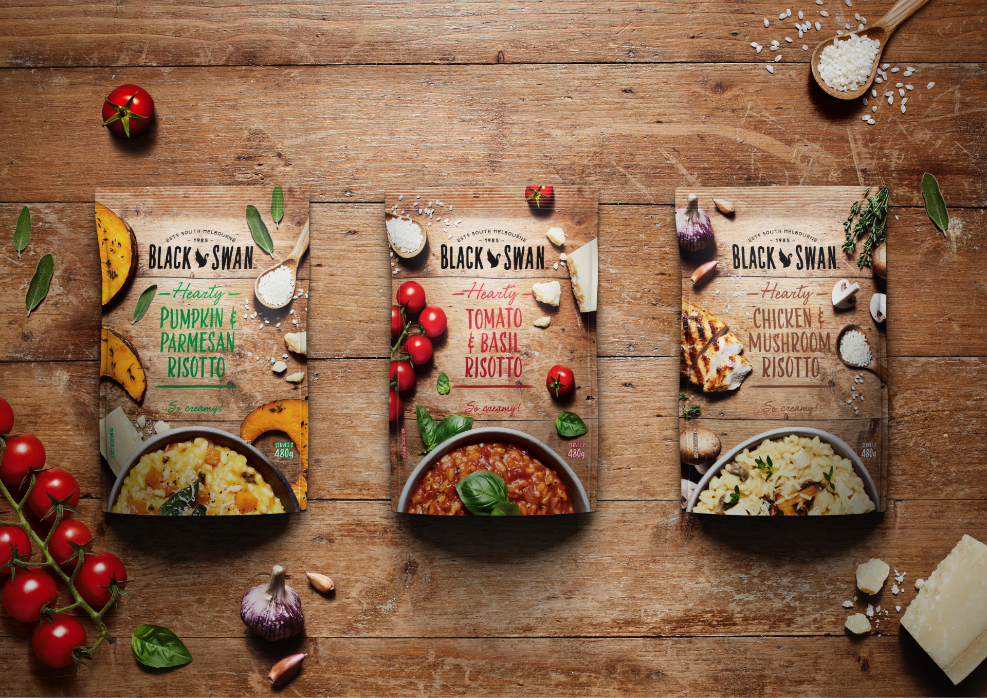 Black Swan Hearty Risotto packaging range, surrounded by various raw ingredients on a wooden table.