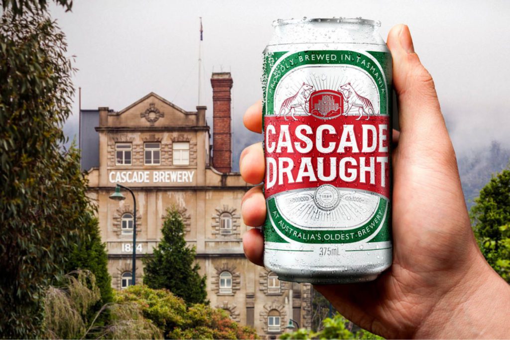 Hand holding Cascade Draught can up against image of Cascade Brewery