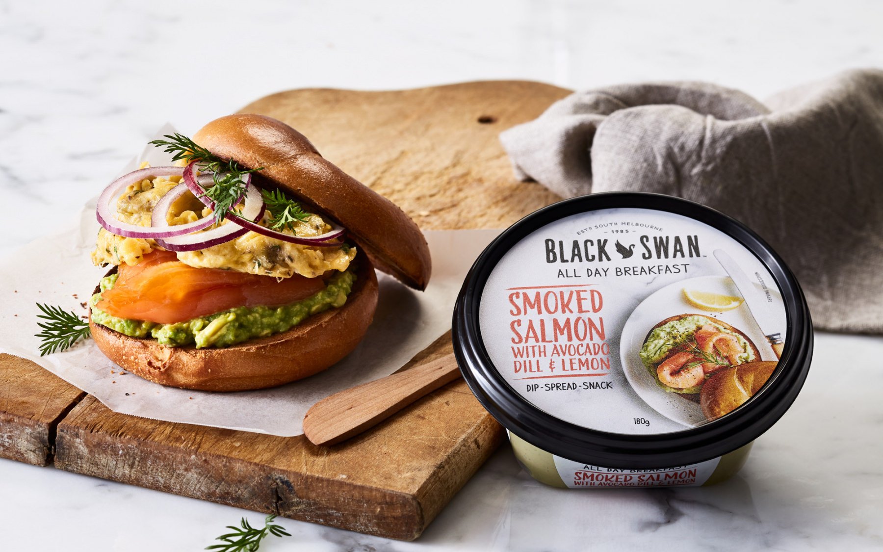 Image of a bagel with salmon and avocado next to Black Swans smoked salmon dip.