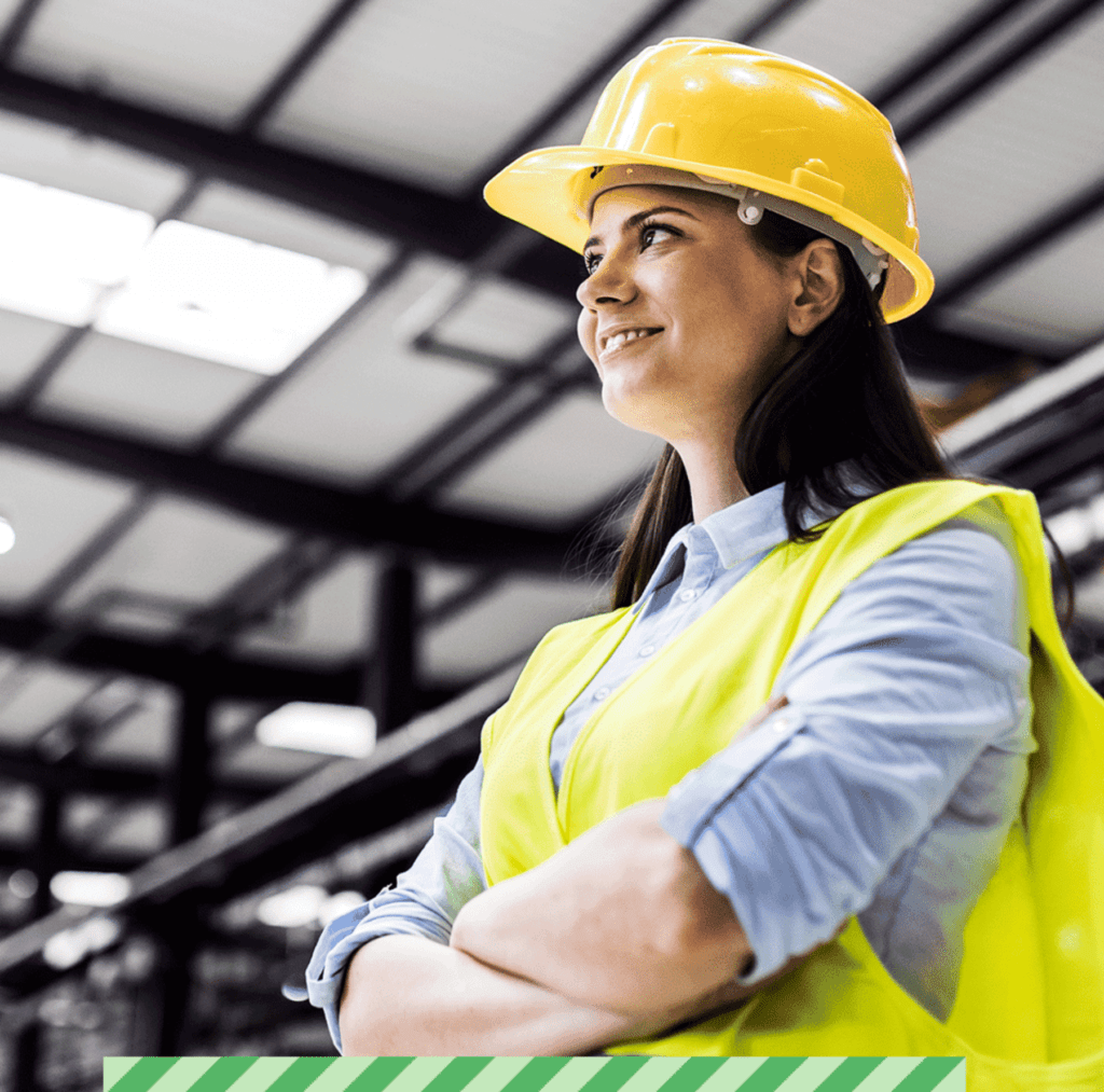 Image of a women wearing a hi-vis hard hat and vest within a warehouse environment.