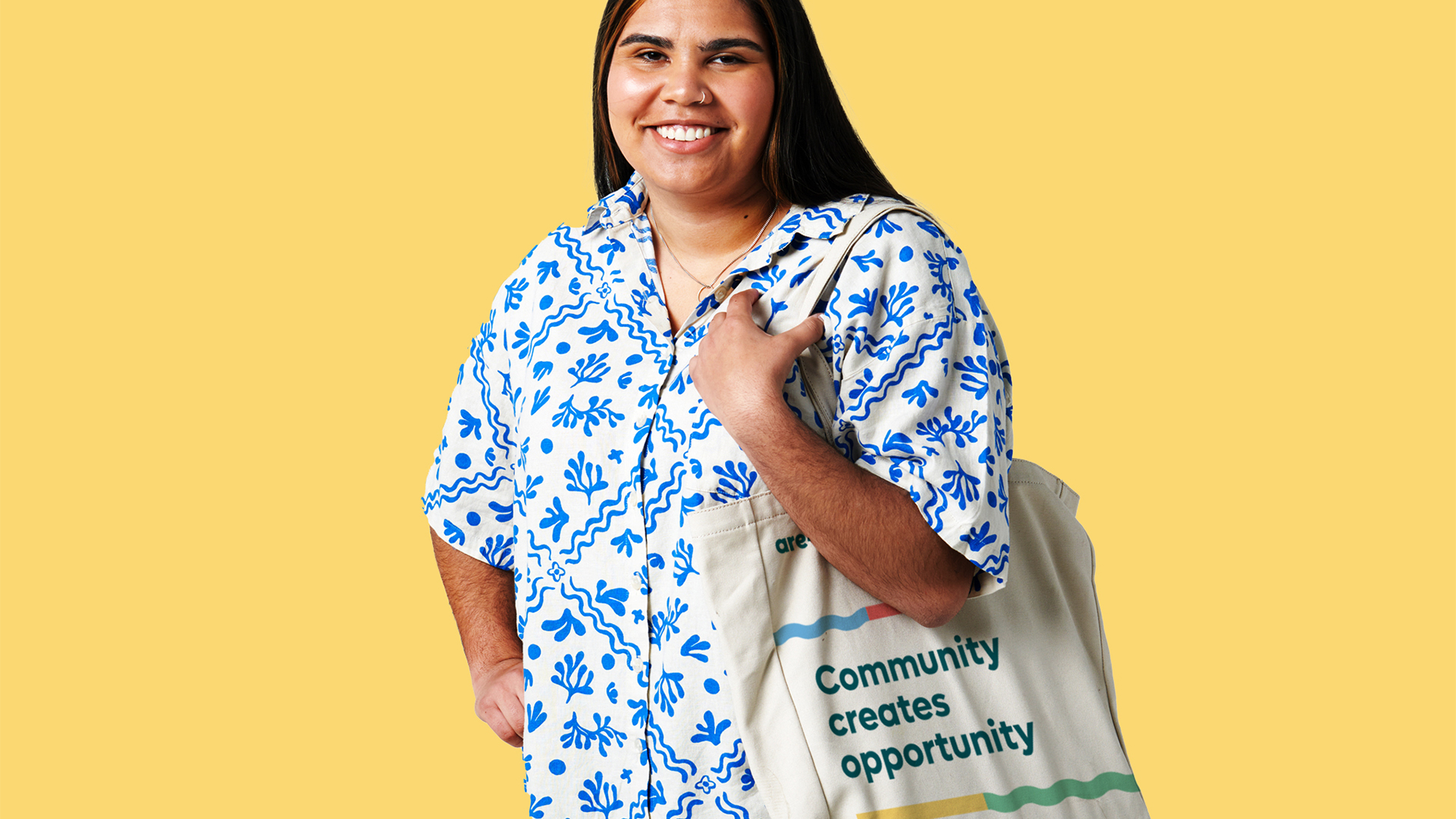 Young edgy first nations person carrying are-able tote bag, yellow background